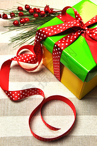 黄色和绿色的圣诞节日礼物用红色圆点丝带和冬青装饰包裹在白色和灰图片