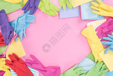 粉红色背景上凌乱散落的多色抹布和橡胶手套的顶视图图片