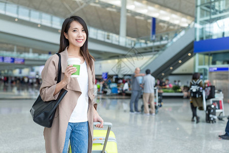 香港国际机场内持有行李和咖啡的妇女含图片