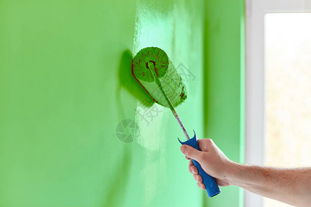 带油漆滚筒的男手绘墙粉刷公寓用图片