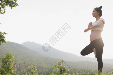 女亚洲孕妇在公园的绿草上练习瑜伽产前锻炼产妇健身健康生活方式图片
