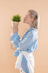 妇女持有植物锅和站在远离蜜蜂的生态衣着中的植物和站立状况简介图片