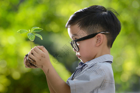 儿童抱着良好环境的希望将幼年植高清图片