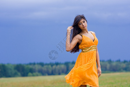 美丽的黑发年轻女子站在田野上图片
