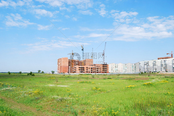 正在建造的住宅建筑和四架起重机与绿的天空对冲图片