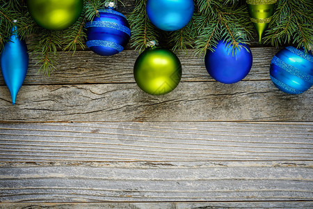 在旧木板上装饰蓝色和绿色首饰的圣诞fir树枝边框图片