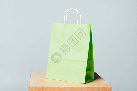 在木板上一个绿色小购物袋在白色夏季销背景图片