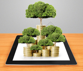 平板电脑秀金钱树从金钱中生长的概念背景图片