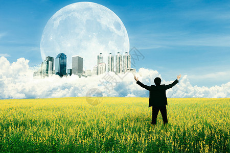 站在田地上看未来城市的商人在云中看图片