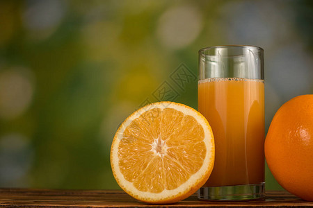 玻璃杯中的橙汁和木桌上的橙子图片