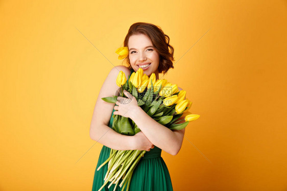 面带黄色郁金香花的微笑着女人的肖像在橙色与图片