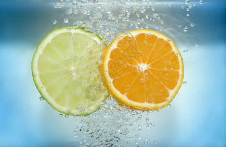 柠檬和橘子片在水中与蓝色背景上的气泡图片