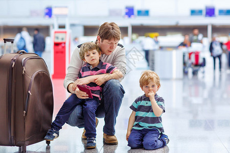 疲惫的父亲和两个弟在机场一起旅行心烦意乱的家人等待因飞行员图片