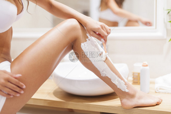 女人在浴室里剃腿的特写图片