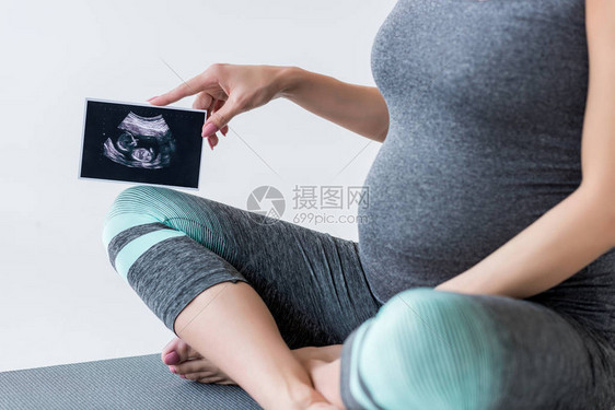 穿着运动服的孕妇的裁剪视图显示未出生婴儿的超声波扫图片