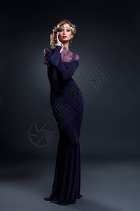 金发美女穿着深紫色的雪佛兰蕾丝裙和饰品工作室在暗底背景拍图片