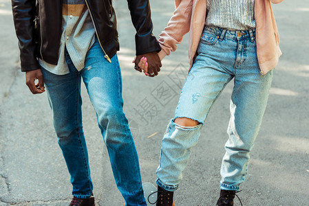 穿着时装鞋和牛仔裤的夫妇在长板上站在一起并握背景图片