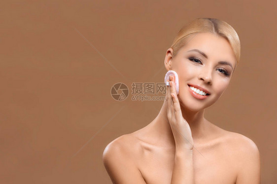 美丽的微笑女人皮肤完美用粉扑化妆图片