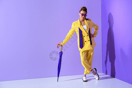 身穿时尚黄色西装紫色雨伞潮流超紫外线背景的图片