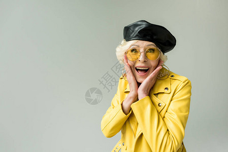 穿着黄色夹克和皮革贝雷帽的时髦兴奋的高级妇女图片