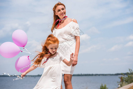 身穿白裙子的美丽的幸福母亲和女儿在图片