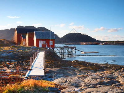 传统渔村岩石岛海岸的乡镇红白色建筑在春日温暖的阳光背景图片