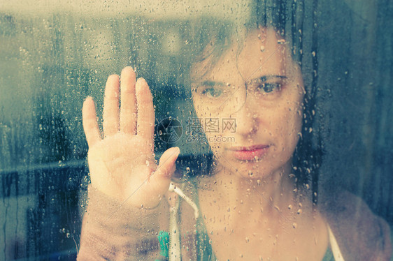 美丽的女人站在窗前带着雨图片