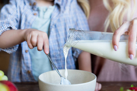 母亲和儿子在早餐碗里倒牛奶的短片图片