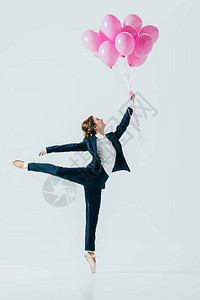 穿着西装和芭蕾舞鞋手持粉色气球孤立在灰色上的图片