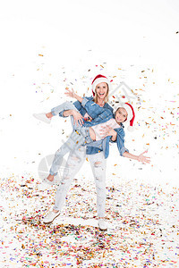 快乐的母亲和女儿穿着圣诞礼帽在圣诞节上涂着面条图片