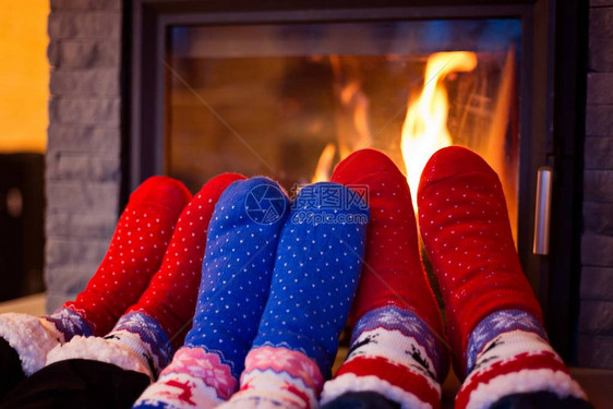 一家人穿着羊毛袜在家里的壁炉旁暖脚图片