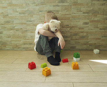 可怜的小男孩坐在地板上与一个街区图片素材