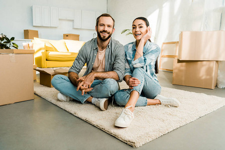 丈夫和妻子坐在地板上在为新房子打包后微图片