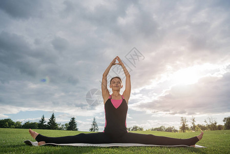 放松的女人坐在广角坐姿前弯瑜伽姿势在公园图片