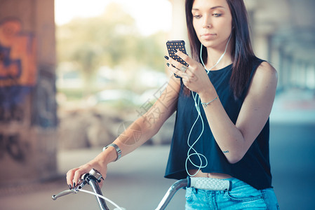 利用自行车和智能手机在户外监听音乐的直发女郎使用自行车图片