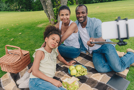年轻非裔美国人家庭在公园野餐期间一起休息时采取自拍行为图片