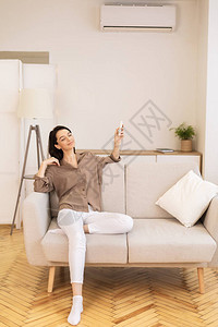 年轻女坐在家沙发垂直图像复制空间时图片