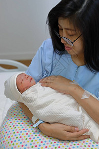 亚洲女母亲在医院分娩新生儿后抱着和看着一个充图片