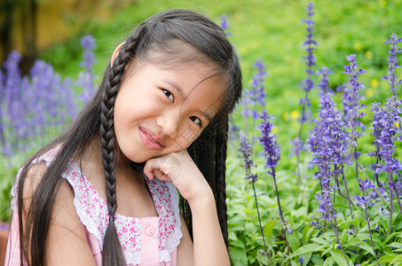 亚洲小女孩蹲在公园的花丛中图片
