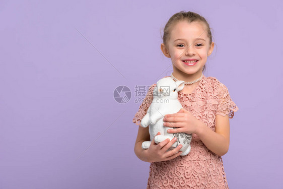 带着兔子雕像的小女孩在紫罗兰上被图片