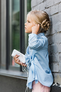 手持秋叶少女耳机中可爱孩子的一面手持智能手机背景