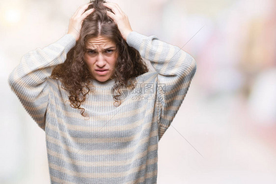 美丽的黑发卷年轻女孩穿着冬季毛衣在孤立的背景下遭受头痛绝望和压力图片