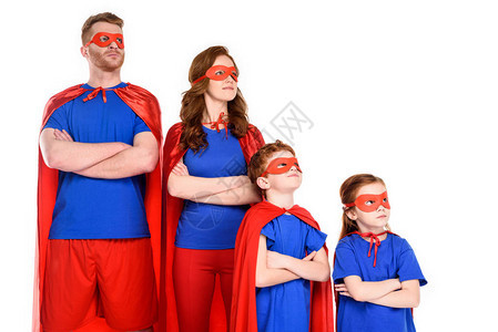 有自信的超级英雄家庭穿着服装站在十字手双臂眼睁地看着图片