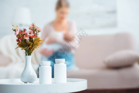 装有药丸花瓶中的鲜花和母亲在家中喂图片