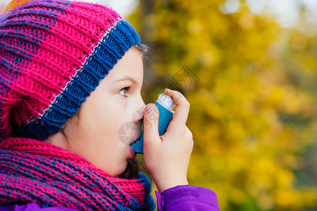 女孩在秋日使用吸入器治疗哮喘发作呼吸系统疾病的吸入治疗浅景深儿童图片