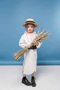 可爱的小女孩站着连衣裙和稻草船图片