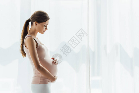 孕妇闭着眼睛摸肚子的侧视图图片