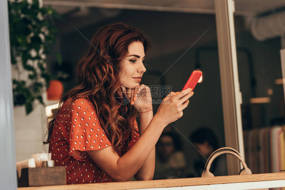 在咖啡馆使用智能手机的年轻女图片