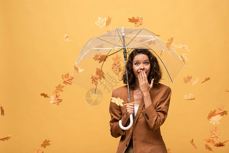 穿着棕色夹克的卷发女人被惊吓拿着雨伞在落图片
