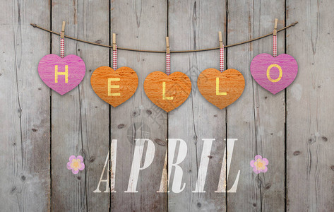 你好四月写着挂在粉红和橙色的心上以及风化的木图片